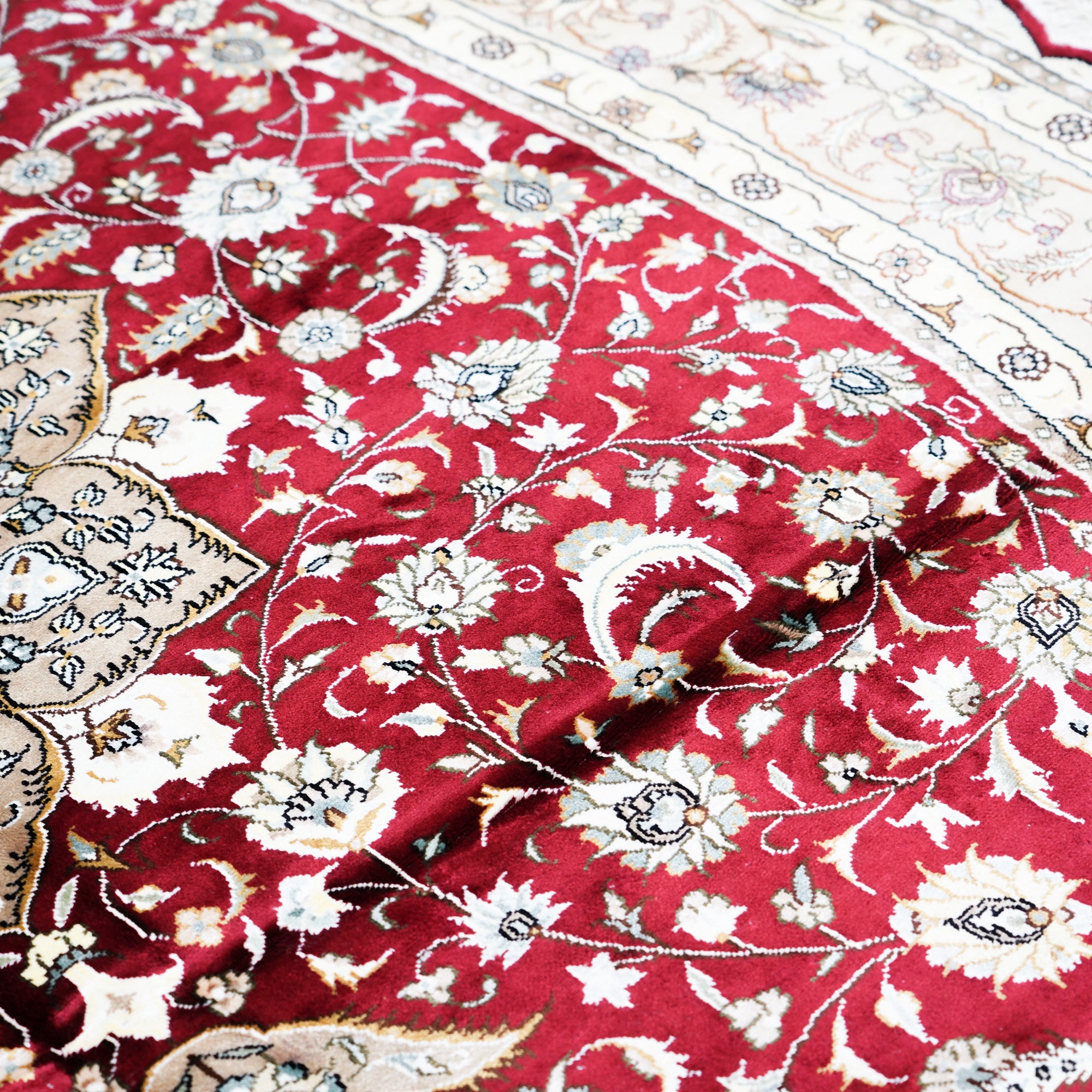 Close-up of a red floral patterned rug with intricate designs.
