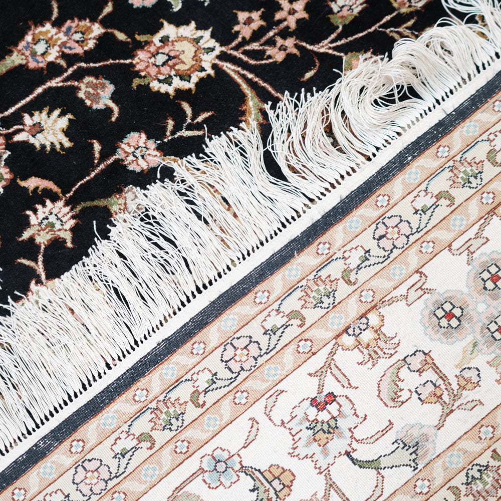 Close-up of two patterned rugs with fringes and floral designs.
