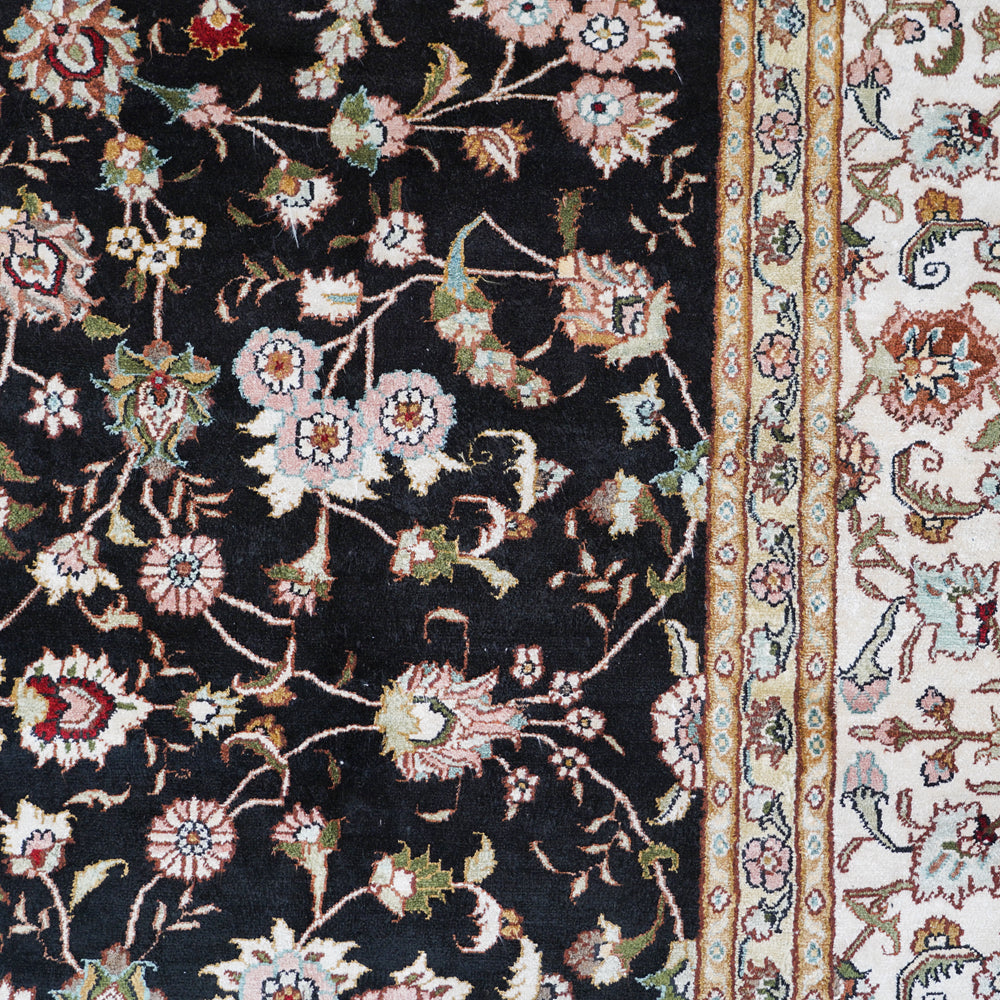 Close-up of a floral-patterned rug with intricate designs on a black background.